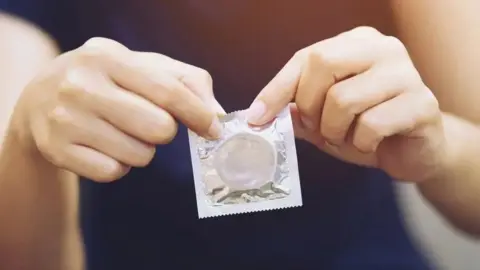 Getty Images Close up of hands holding a condom. 